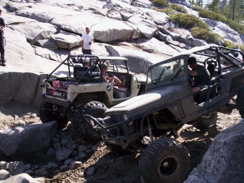 1989 Ford Bronco - Two off-road vehicles are shown maneuvering through a challenging rocky landscape with steep inclines.