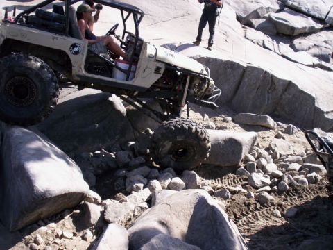 1989 Ford Bronco - An off-road vehicle tackles a challenging rocky terrain, with another vehicle in the background.