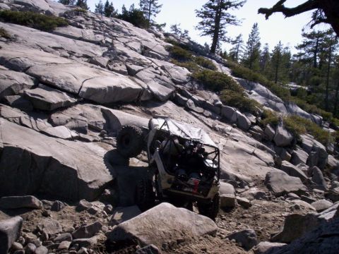 1989 Ford Bronco - A modified off-road vehicle navigates a steep, boulder-strewn mountain trail.