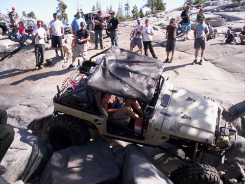 1989 Ford Bronco - An off-road vehicle maneuvers through a rocky terrain with spectators watching.