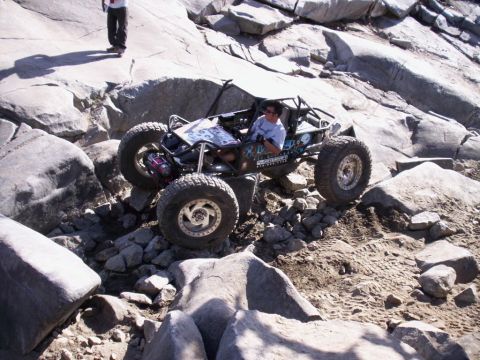 1989 Ford Bronco - A custom off-road buggy tackles a challenging rocky trail with large boulders and loose dirt.