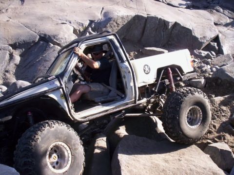 1989 Ford Bronco - A modified off-road vehicle navigates a rocky terrain, its suspension and large tires.