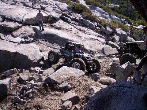 1989 Ford Bronco - Two off-road vehicles navigate a challenging rocky trail on a sunny day.