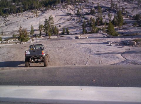 1989 Ford Bronco - Pickup truck with off-road modifications parked on a rocky landscape with scattered trees.