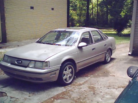 1992 Ford Taurus - A 1992 Ford Taurus is parked on a concrete driveway next to a brick building.