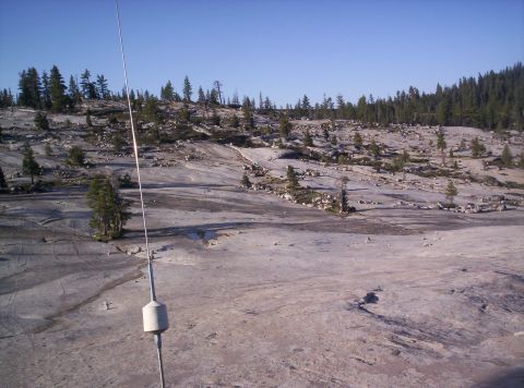 1989 Ford Bronco - Expansive rocky terrain dotted with pine trees and a prominent antenna against a clear sky.