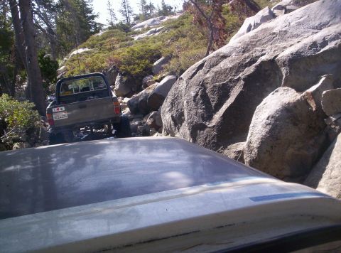 1989 Ford Bronco - A pickup truck navigates a challenging, rocky off-road path under a clear sky.