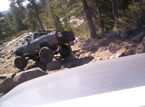 1989 Ford Bronco - A modified pickup truck is shown off-roading on a steep, rocky trail.