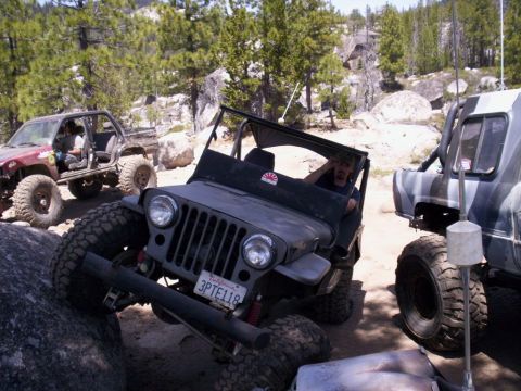 1989 Ford Bronco - Off-road Jeeps navigate a rocky trail, with multiple vehicles visible in the scene.