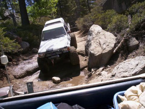 1989 Ford Bronco - This vehicle is navigating a challenging off-road trail with significant mud and rocks.