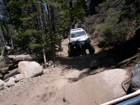 1989 Ford Bronco - An off-road SUV navigates a rocky, wooded trail.