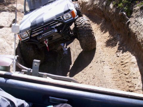 1989 Ford Bronco - This SUV is tackling a challenging off-road trail with steep inclines and loose dirt.