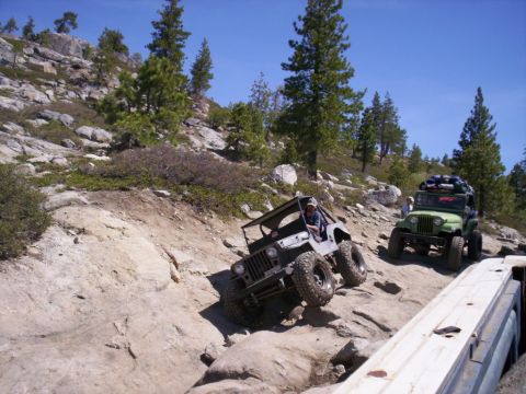 1989 Ford Bronco - Off-road vehicles tackle a challenging rocky terrain on a sunny day.