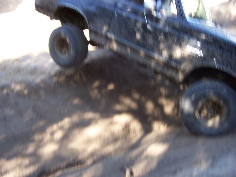 1991 Ford Bronco - A black 1991 Ford Bronco navigates a dirt trail, with its front passenger wheel lifted off the ground.