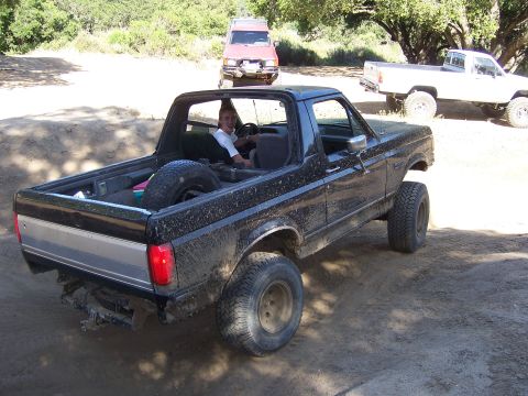 1991 Ford Bronco - Off-roading in a lifted 1980s Ford Bronco, with other vehicles present on the trail.