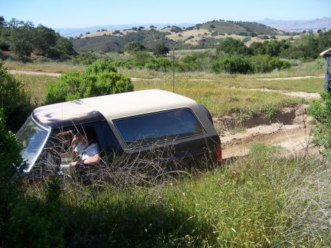 1991 Ford Bronco - A Ford Bronco navigates a challenging off-road terrain with rolling hills in the background.
