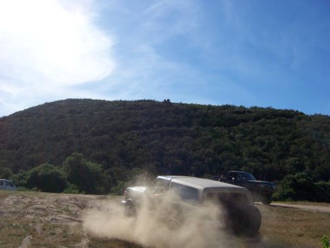 1991 Ford Bronco - A white 1991 Ford Bronco navigates a dusty off-road trail with another vehicle visible in the background.