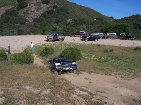 1991 Ford Bronco - A group of SUVs, including a black 1990 Ford Bronco, navigate a dirt trail during an off-road event.