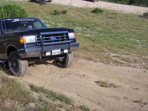 1991 Ford Bronco - A black 1991 Ford Bronco navigates a dusty trail during an off-road event.