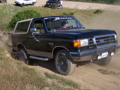 1991 Ford Bronco - 1991 Ford Bronco navigating a dusty off-road trail with other vehicles present.
