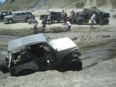 1987 Suzuki Samurai - Multiple off-road vehicles, including a Suzuki Samurai, are stuck in the mud at an outdoor event.