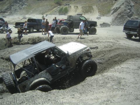 1987 Suzuki Samurai - Off-road vehicles navigate a challenging muddy terrain, with several vehicles requiring assistance.