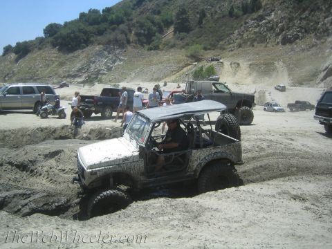 1987 Suzuki Samurai - A white 1987 Suzuki Samurai navigates a sandy obstacle course, getting stuck in the mud.