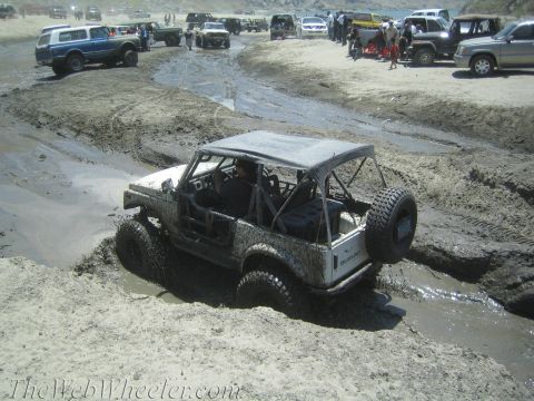 1987 Suzuki Samurai - Suzuki Samurai tackling a challenging mud course with multiple vehicles present.