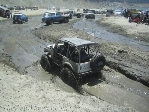 1987 Suzuki Samurai - A Suzuki Samurai navigates a muddy track alongside other off-road vehicles.
