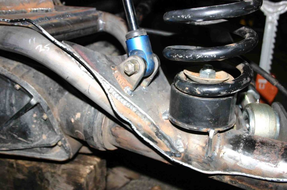 Close-up of rear axle with coil spring and blue shock absorber mount