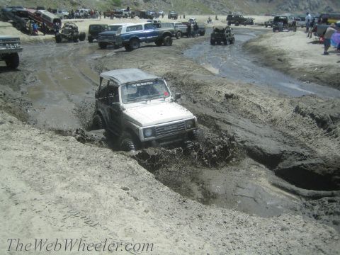1987 Suzuki Samurai - A Suzuki Samurai navigates a muddy track with several other vehicles present.