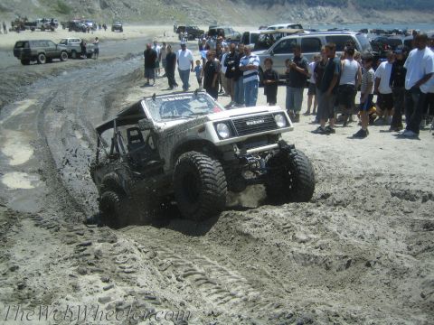 1987 Suzuki Samurai - Suzuki Samurai navigates a muddy track on a beach with spectators nearby.