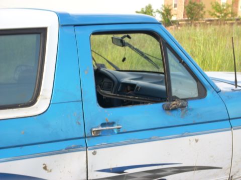 1992 Ford Bronco - The interior of a blue and white pickup truck is visible through the open driver's side door.