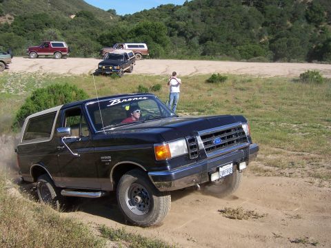 1991 Ford Bronco - Black 1987 Ford Bronco navigating an off-road trail with other vehicles present.