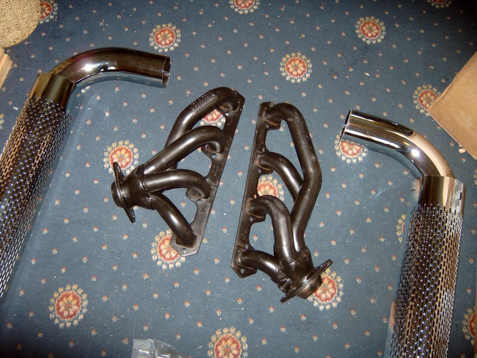 Set of exhaust headers and chrome pipes laid on a patterned carpet