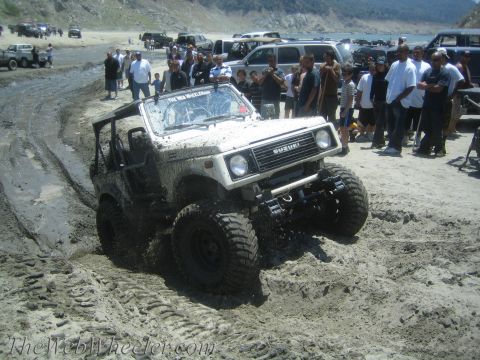 1987 Suzuki Samurai - This 1987 Suzuki Samurai is navigating a muddy off-road course with spectators watching.
