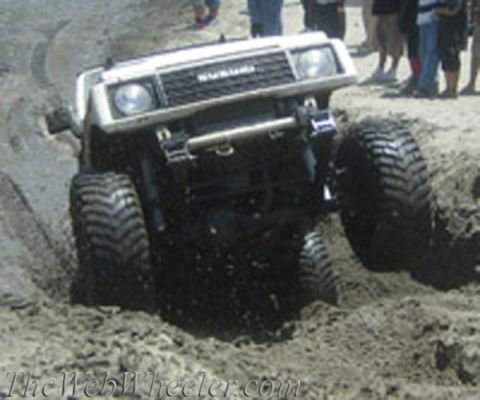 1987 Suzuki Samurai - This Suzuki Samurai is navigating a challenging sandy terrain, with onlookers observing the off-road action.