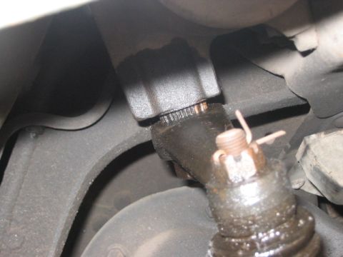 1991 Ford Bronco - Close-up of a greasy automotive steering linkage assembly, showing a nut and cotter pin.