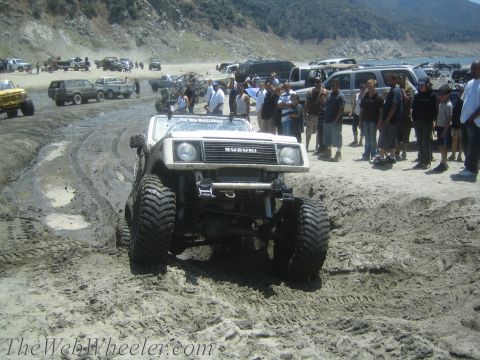1987 Suzuki Samurai - Modified 1987 Suzuki Samurai navigates a muddy and sandy terrain with spectators nearby.