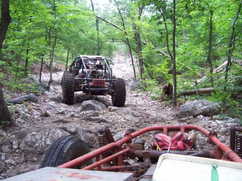 1989 Ford Bronco II - Two off-road buggies navigate a rocky, wooded trail.
