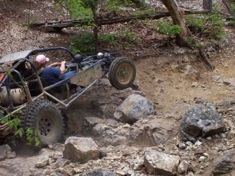 1989 Ford Bronco II - This off-road buggy navigates a challenging rocky incline on a wooded trail.