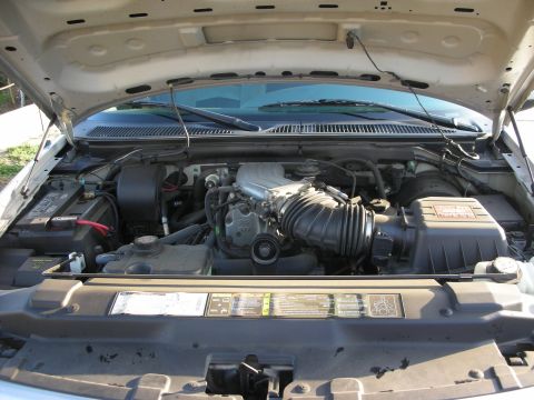 1998 Ford Crown Victoria - Open hood over a largely stock Ford modular V8 engine bay, with the cast intake manifold and Ford-badged coil cover, black air intake tube…