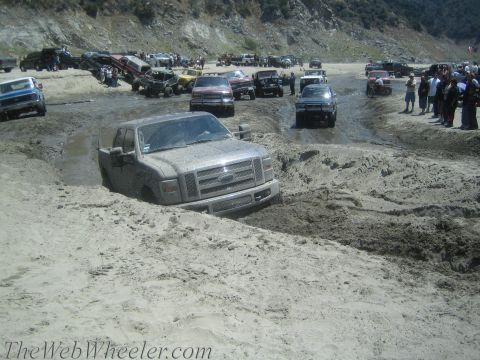 1987 Suzuki Samurai - Multiple vehicles navigate a challenging muddy terrain during an off-road event.