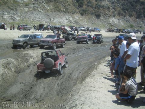 1987 Suzuki Samurai - A group of off-road vehicles gather in a muddy area, with spectators watching.