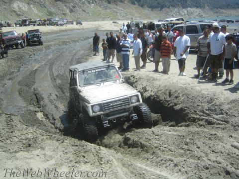 1987 Suzuki Samurai - A group of people watch as a white 1987 Suzuki Samurai navigates a muddy off-road course.