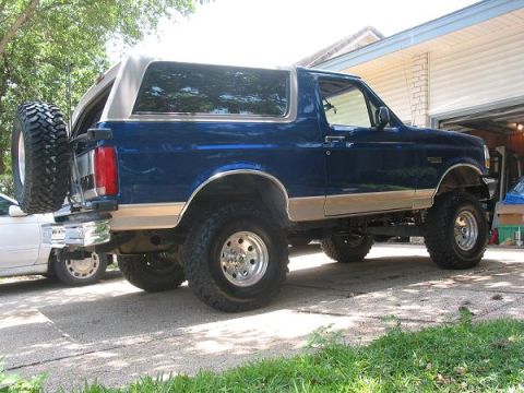 1996 Ford Bronco - A lifted 1996 Ford Bronco is parked in a driveway with a spare tire mounted on the rear.