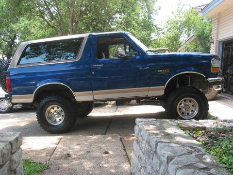 1996 Ford Bronco - Side view of a lifted 1996 Ford Bronco with blue paint and tan trim.