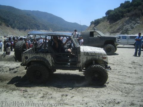 1987 Suzuki Samurai - Off-road vehicles gathered near a lake on a sunny day, with one Suzuki Samurai covered in mud.