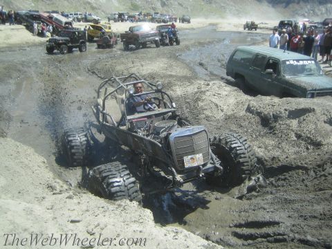 1987 Suzuki Samurai - A custom buggy navigates a muddy terrain with other vehicles in the background.