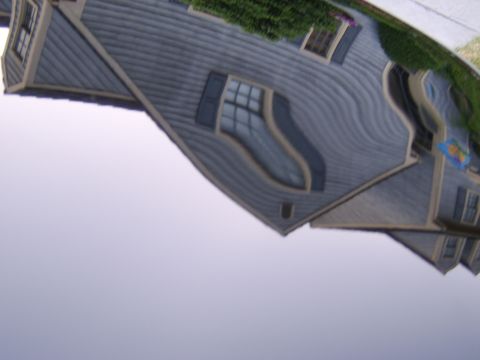 1996 Mercury Grand Marquis - Reflection of a house in a distorted surface, possibly a car's hood or a funhouse mirror.
